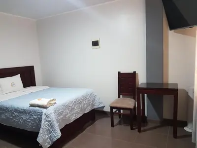 a bedroom with a bed and a table and a chair at Hotel Luz de Luna in Atico
