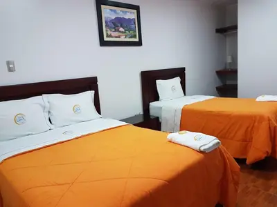 two beds with orange sheets in a room at Hotel Luz de Luna in Atico