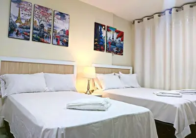 two beds with white sheets in a room at Residencial Suiza in Lima