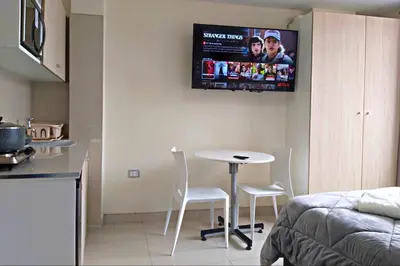 a kitchen with a table and chairs and a tv on the wall at Residencial Suiza in Lima