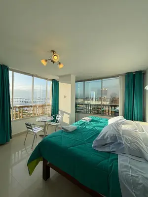 a bedroom with a green bed and a balcony at El Gamonal - Paracas in Paracas