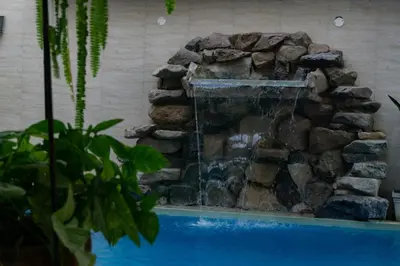 a waterfall in a pool with a stone wall at El Gamonal - Paracas in Paracas