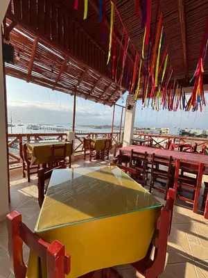 a yellow table and chairs in a restaurant with flags at El Gamonal - Paracas in Paracas