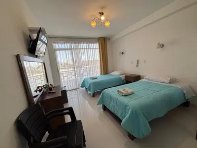 a bedroom with two beds and a chair and a window at Mar Azul in Paracas