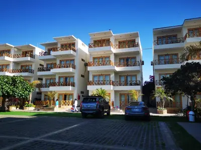 a large white building with cars parked in front of it at Hotel Emancipador in Paracas