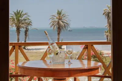 a table with wine bottles and glasses on a balcony at Hotel Emancipador in Paracas