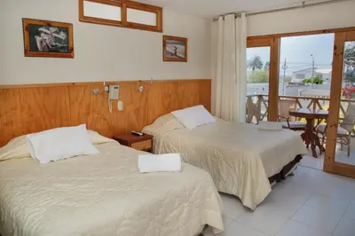two beds in a hotel room with a balcony at Hotel Emancipador in Paracas