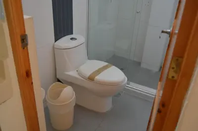 a bathroom with a toilet and a glass shower at Hotel Los Flamencos in Paracas