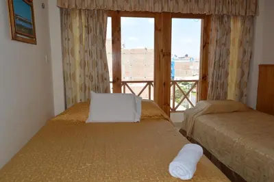 a bedroom with two beds and a window with a view at Hotel Los Flamencos in Paracas