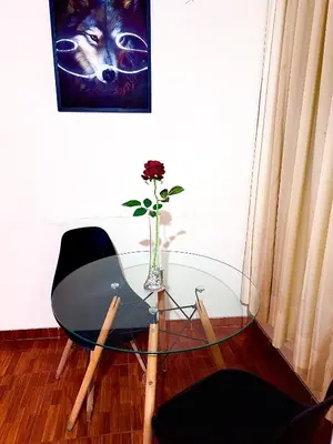 a glass table with a chair and a vase with a flower at 200. Hermoso Departamento con Servicios Incluidos en Chorrillos in Lima