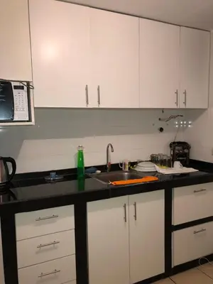a kitchen with white cabinets and a sink at Qurpawasi in Lima