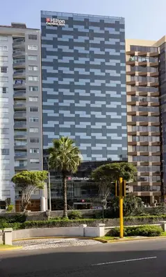 a tall building with palm trees in front of a street at Hilton Garden Inn Lima Miraflores in Lima