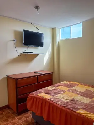 a bedroom with a bed and a tv on the wall at Hospedaje Anais in Pisco