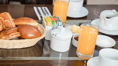 a table with a basket of bread and orange juice at KASAS DEL INKA MACHUPICCHU in Machu Picchu