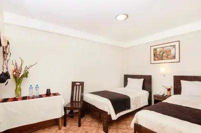 a hotel room with two beds and a table at KASAS DEL INKA MACHUPICCHU in Machu Picchu