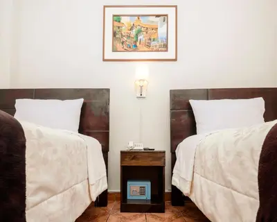a bedroom with two beds and a table with a picture at KASAS DEL INKA MACHUPICCHU in Machu Picchu