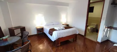 a bedroom with a bed and a table and a mirror at Elsa Wasi Cusco in Cusco