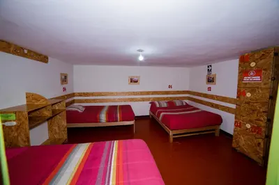 a room with two beds and a couch in it at Ukukus Hostel in Cusco