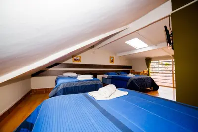 a room with three blue beds in a attic at Ukukus Hostel in Cusco