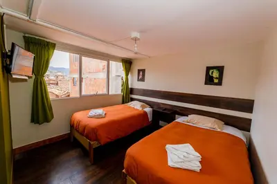 a hotel room with two beds and a window at Ukukus Hostel in Cusco