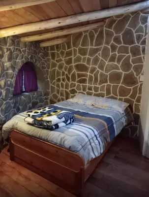 a bed in a room with a stone wall at Illa Wasi Sacred Valley in Urubamba