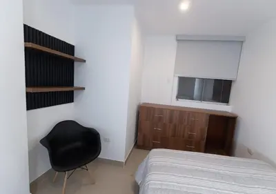 a bedroom with a bed and a black chair at Moderno Departamento en Barranca in Barranca