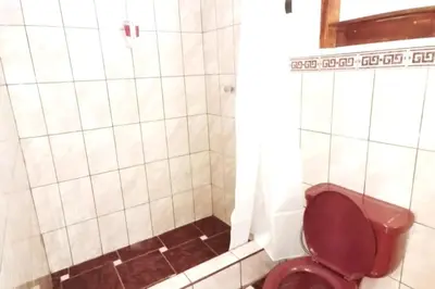 a bathroom with a red toilet and a shower at APARMENT SAMANA HOUSE OLLANTAYTAMBO in Ollantaytambo