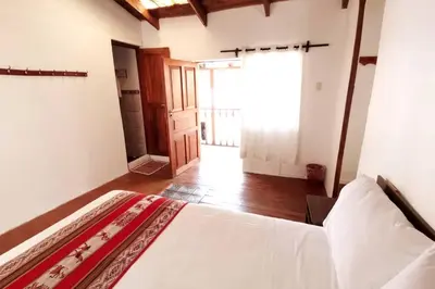 a bedroom with a white bed and a large window at APARMENT SAMANA HOUSE OLLANTAYTAMBO in Ollantaytambo