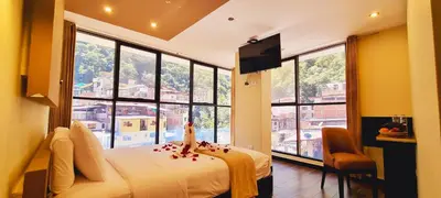 a bedroom with a bed and large windows at Hotel Raices Machupicchu in Machu Picchu