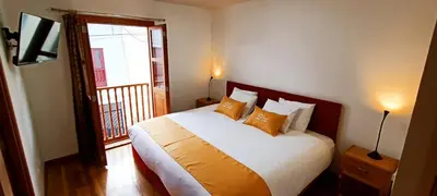 a bedroom with a bed with orange pillows and a balcony at 7th Wonder Apart Hotel Cusco in Cusco