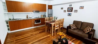 a kitchen and a living room with a table and a couch at 7th Wonder Apart Hotel Cusco in Cusco
