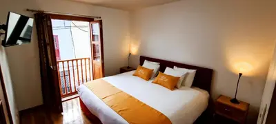 a bedroom with a bed with orange pillows and a window at 7th Wonder Apart Hotel Cusco in Cusco