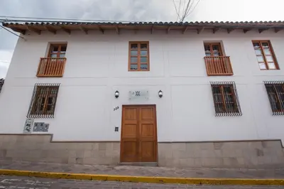 a white building with a brown door and windows at 7th Wonder Apart Hotel Cusco in Cusco