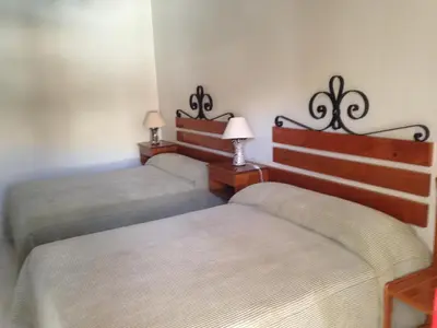 two twin beds in a room with two lamps at Hosteria Suiza in Ica