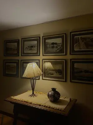 a lamp on a table with pictures on the wall at Hosteria Suiza in Ica