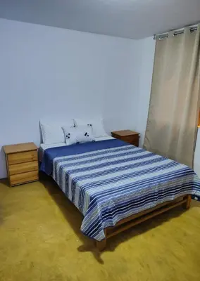 a bedroom with a bed with a blue comforter at Hospedaje Kaihalulu in Punta Hermosa