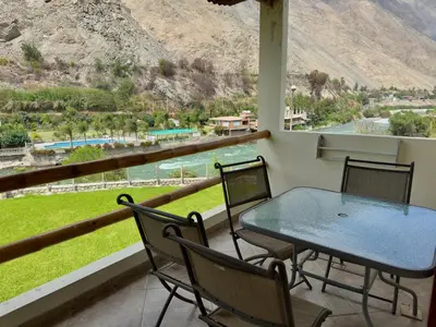 a table and chairs on a balcony with a view at Rio Lindo Ecolodge in Lunahuaná