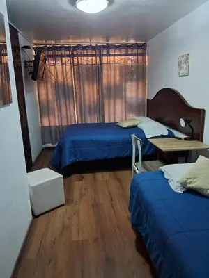 a bedroom with two beds and a table in it at Villas Del Sol Bed & Breakfast in Lima