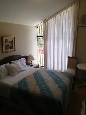 a bedroom with a bed and a large window at Villas Del Sol Bed & Breakfast in Lima