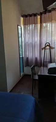 a bedroom with a bed and a chair and a window at Villas Del Sol Bed & Breakfast in Lima