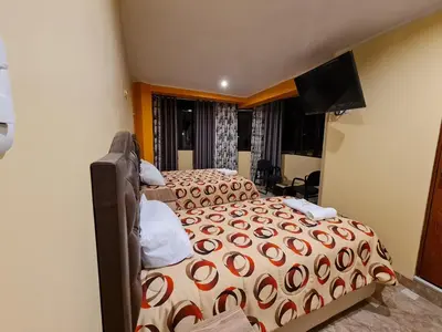 a bedroom with two beds and a flat screen tv at Hostal Tuki Huancayo in Huancayo