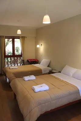 a hotel room with three beds with towels on them at Hotel Garden House Huerta in Limatambo