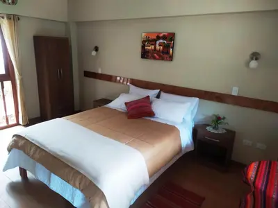 a bedroom with a large bed with white sheets and red pillows at Hotel Garden House Huerta in Limatambo