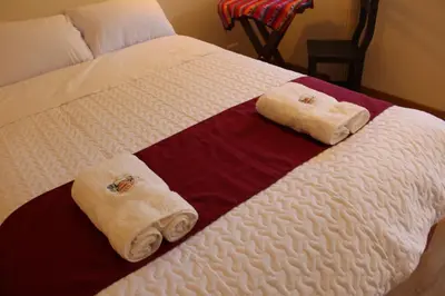 a bed with two folded towels on it at Hotel Garden House Huerta in Limatambo