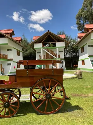 a wooden cart in the grass in front of some buildings at RESORT ALAPA in Huancayo