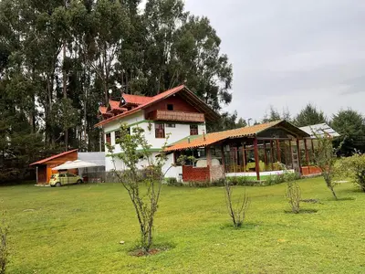 a house in a field with trees in front of it at RESORT ALAPA in Huancayo