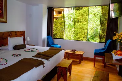 a bedroom with a bed and a large window at Hotel Tara Machupicchu in Machu Picchu