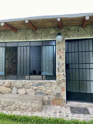 a stone house with black barred windows on it at Las Cabañas de Incahuasi in Lunahuaná
