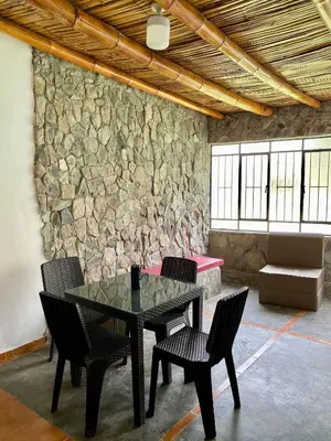 a table and chairs in a room with a stone wall at Las Cabañas de Incahuasi in Lunahuaná