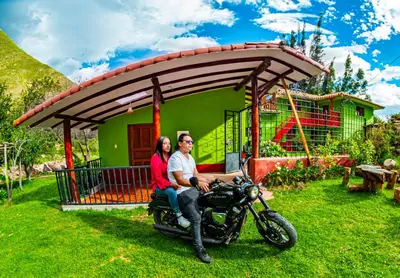 a man and woman sitting on a motorcycle in front of a house at Happy Land Valle Sagrado in Urubamba
